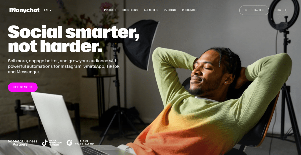 Web page landing screenshot for Manychat featuring the headline "Social smarter, not harder.", a pink Get Started button, partner badges, and a background photograph of a man reclining in an office chair in front of a laptop.